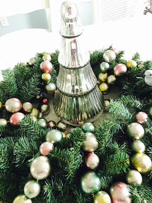 Green wreath with silver tree in middle with pastel garland