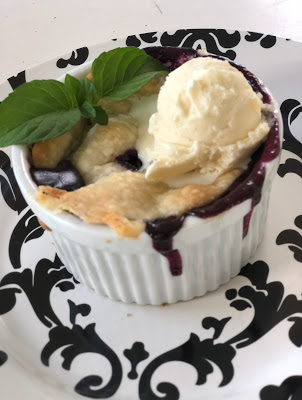 peach blueberry crisp in ramekin topped with vanilla ice cream