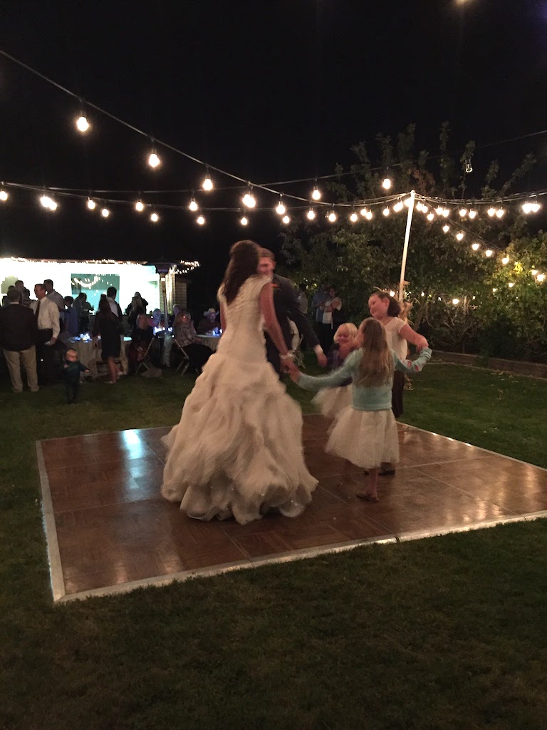bride dancing on outdoor dance floor with kids. Easy outdoor rustic wedding reception. Wedding reception dance floor at home.