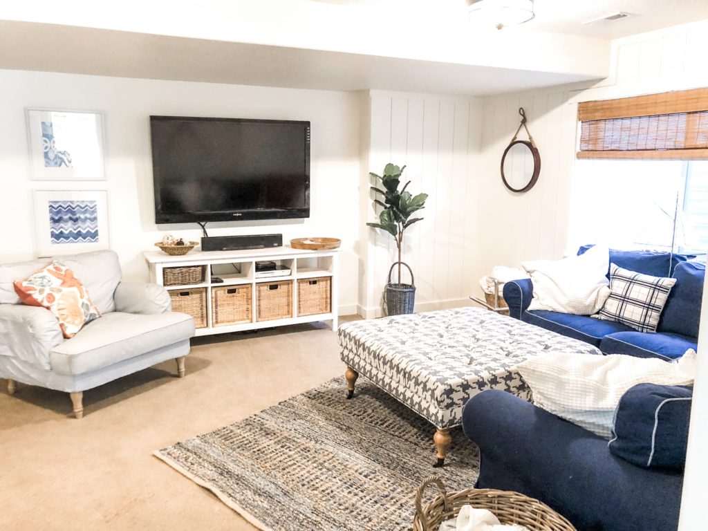 Navy and white basement  makeover with a nautical feel. Bamboo shades, Denim sofa, Blue and white striped side chair. Ikea furniture