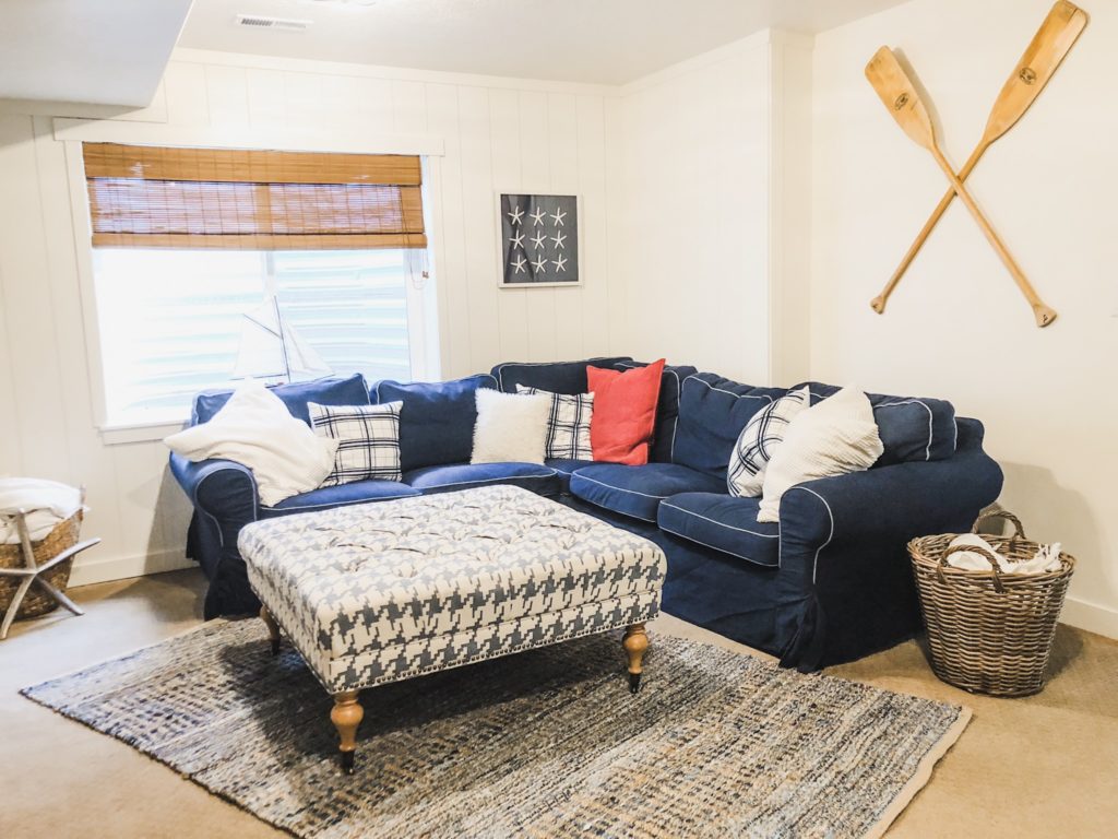 Navy and white basement makeover with a nautical look. Paddle boards hung on the walls, Denim sofa