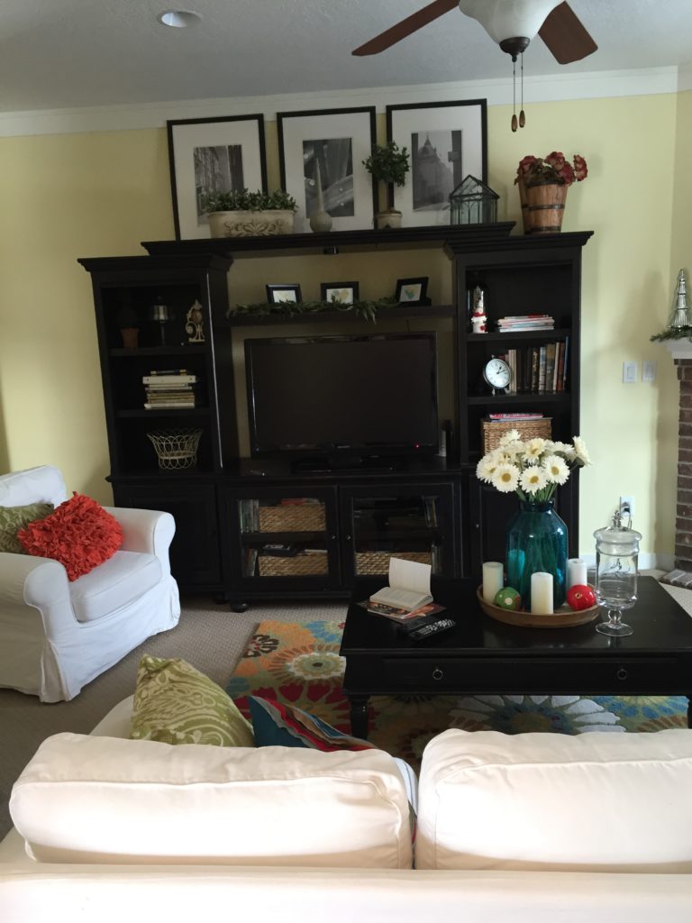 black entertainment center in family room with white sofas