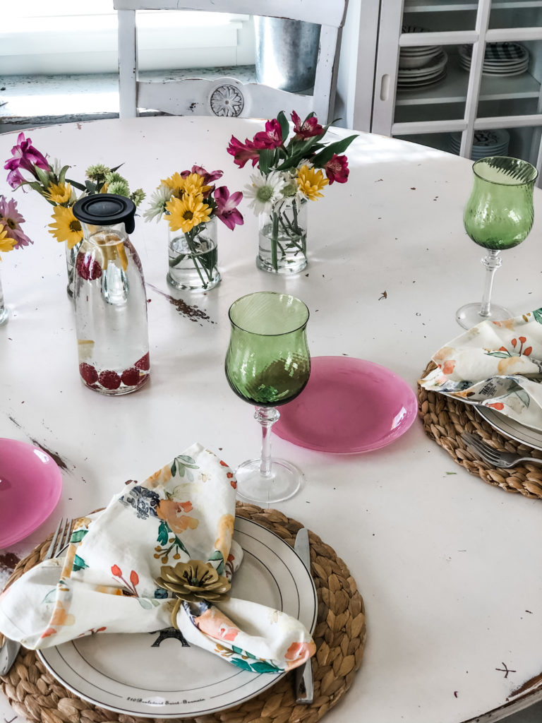 woven placemats, pretty green goblets, floral napkins, grocery store flowers