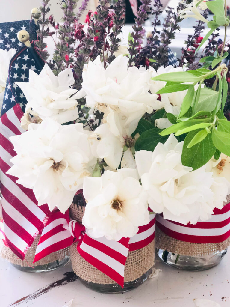 red white blue mason jar with flowers and red and white striped ribbon