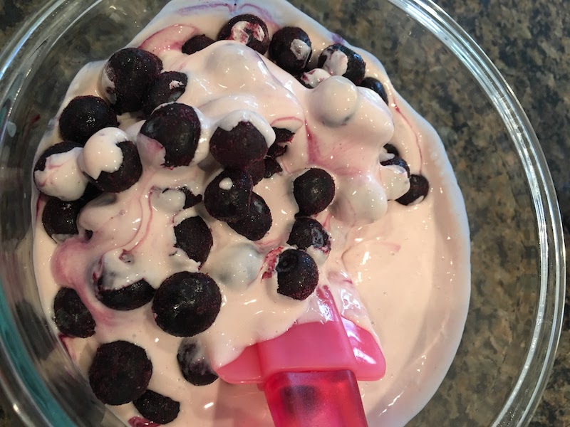 Folding in blueberries to yogurt, cream, honey and juice.