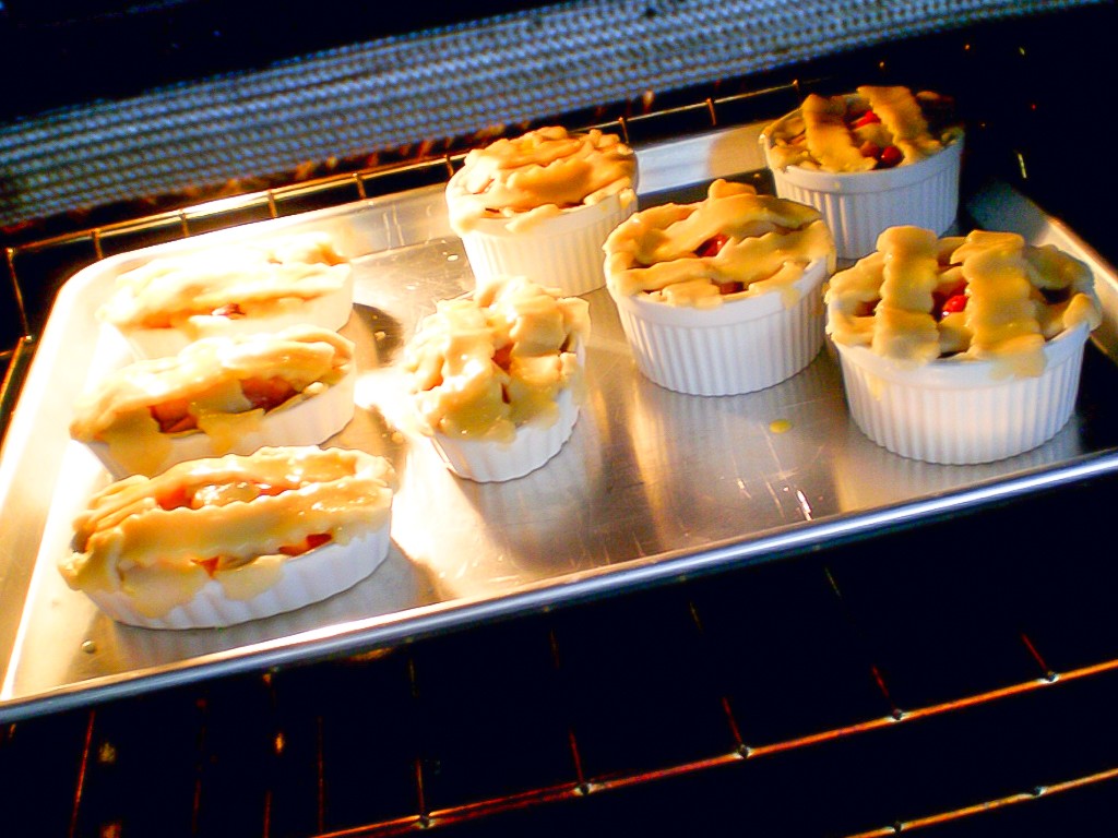 mini peach and raspberry pies in oven