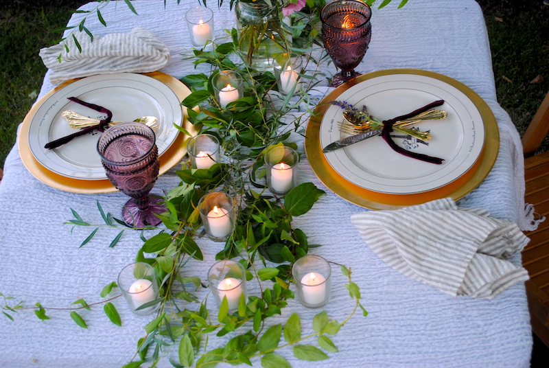 Honey suckle vines laying down the center of the table with votive candles for a romantic outdoor dinner at home