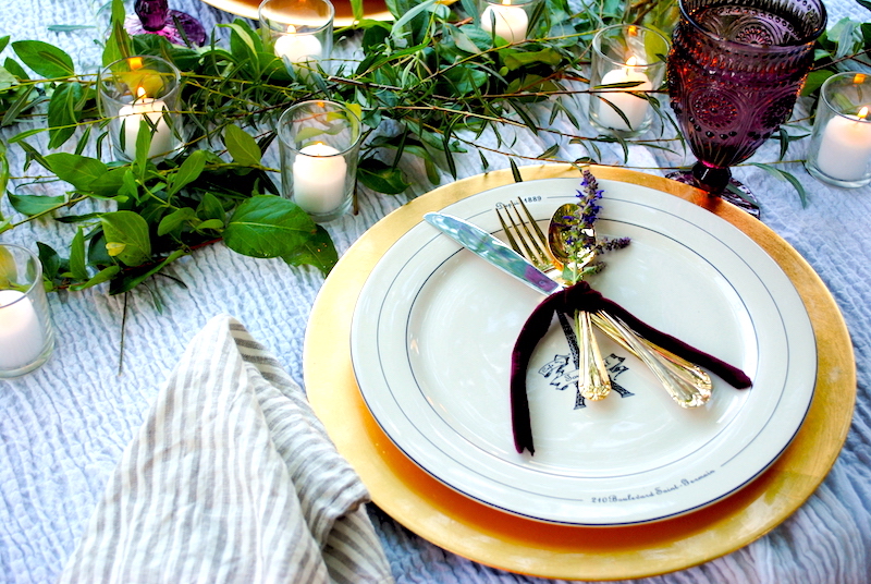 a romantic outdoor dinner for two- French Eiffel tower plates sit atop gold chargers with gold flatware tied with velvet ribbon for