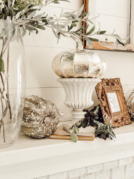 Silver pumpkins on fireplace mantel or mantle. Gold frame, urns