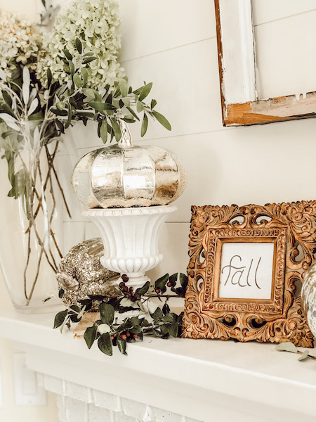 How to decorate fireplace mantel with silver pumpkins gold frame and greenery on fireplace mantle