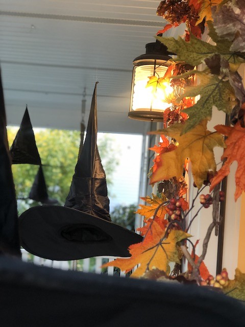 Witch hats hanging on front porch with fall leaves