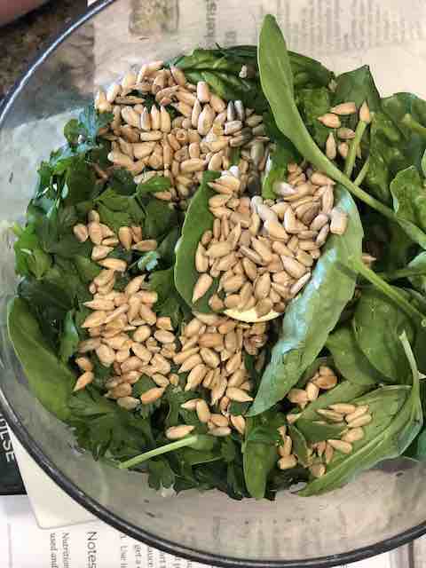 Putting spinach , pine nuts into cuisinart for pesto