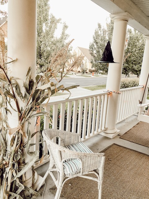 white porch with black witch hats and cornstalks