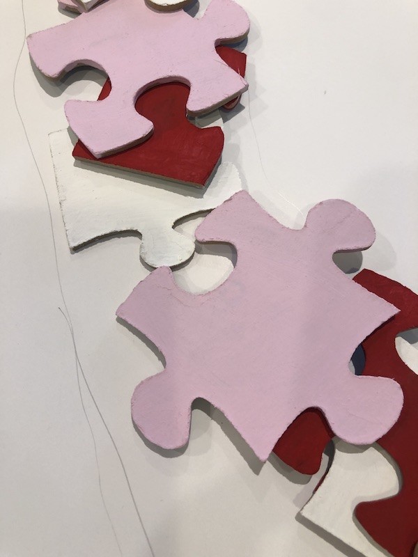 using a pencil to draw on each side of the puzzle pieces for heart wreath