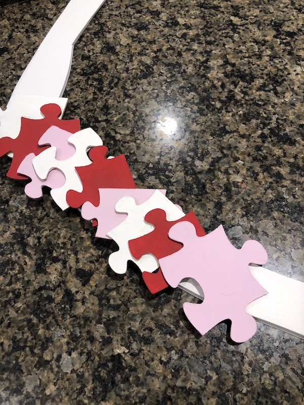 DIY Puzzle heart wreath- puzzle pieces laid out on heart shaped base