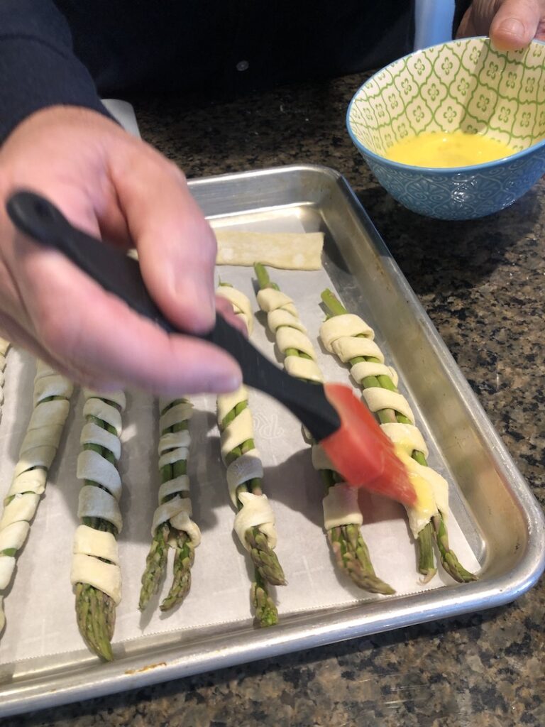 brushing pastry wrapped asparagus  with egg wash