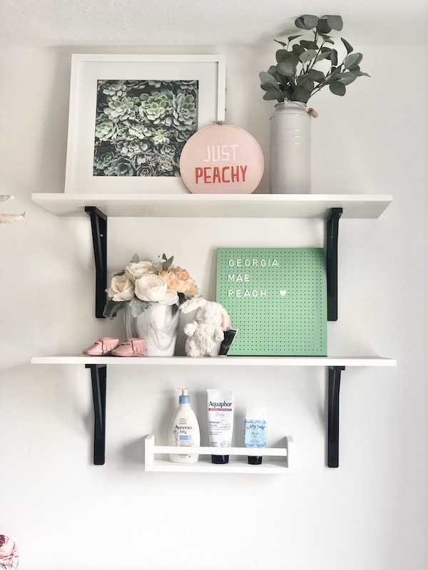 A cute nursery for a new grand baby white shelving with black brackets