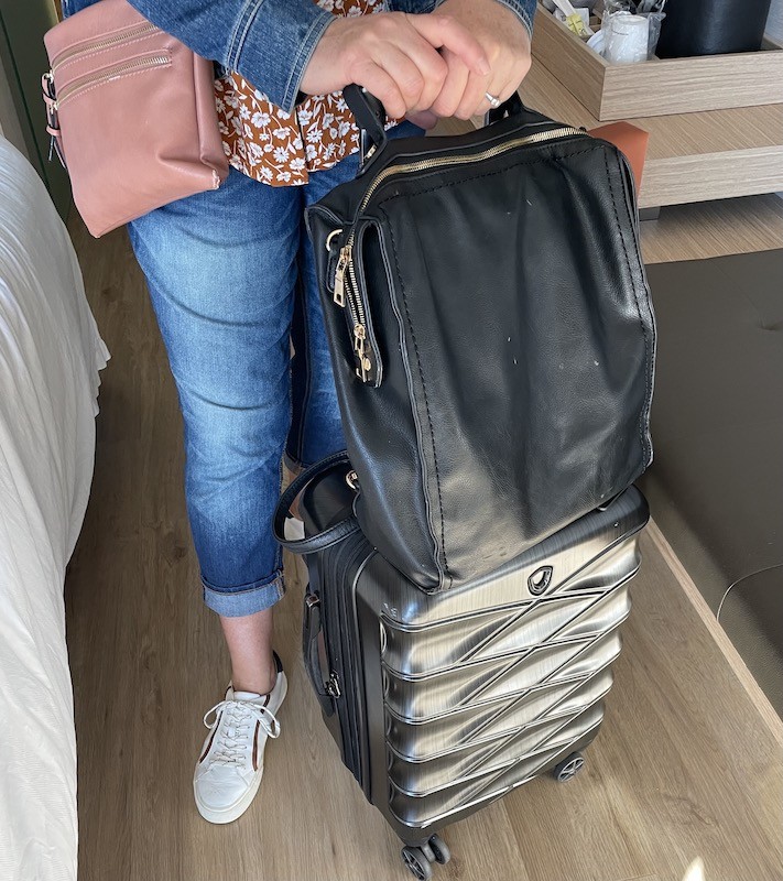 Leather backpack on rolling suitcase madewell sneakers, denim pants and denim jacket for flying on airplane- Karins Kottage