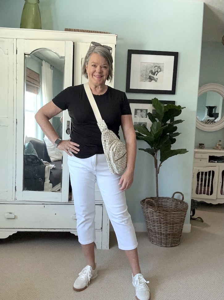 Cream patterned crossbody travel bag paired with white capri pants and black t-shirt for women over 50.