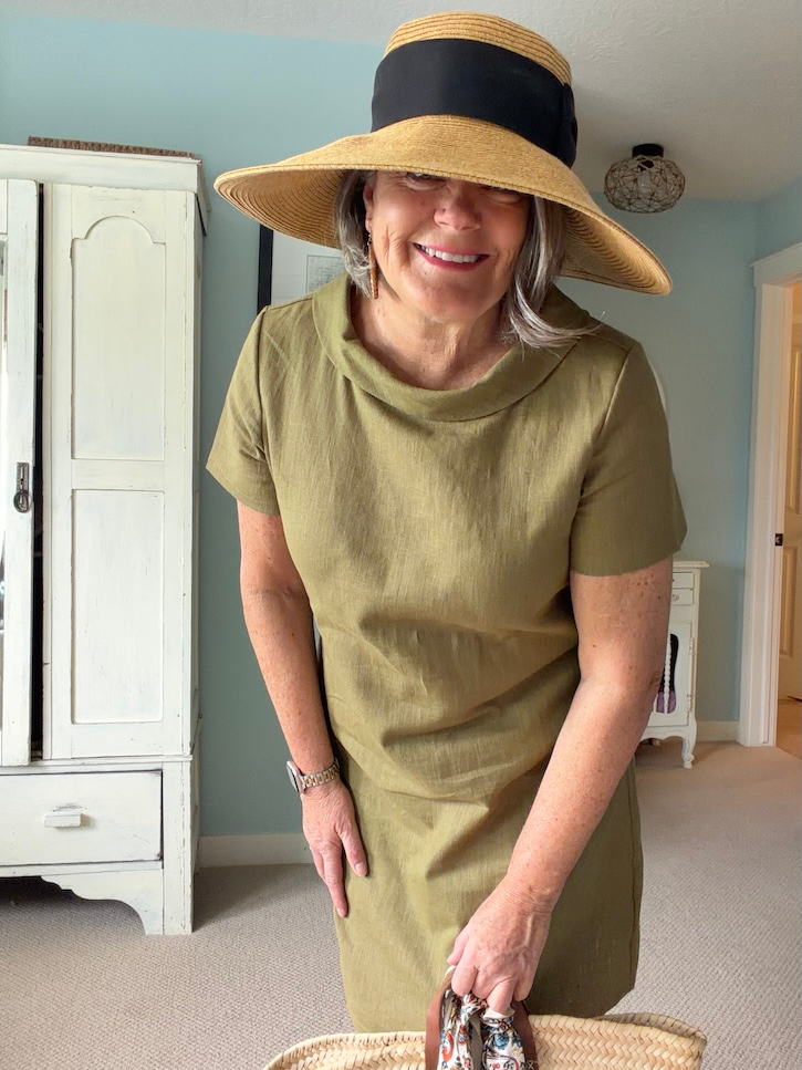Olive green linen dress styled with a large sun hat and statement earrings for summer