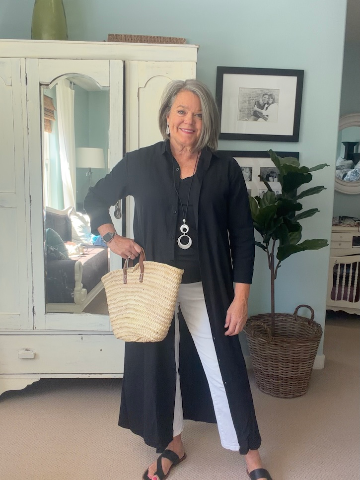Black shirt dress worn open over a black top and white cropped pants