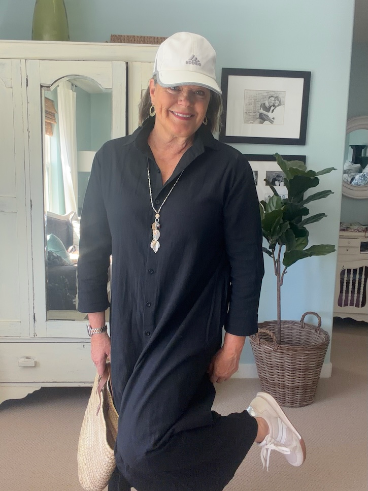 Casual black shirt dress styled with white baseball cap and sneakers