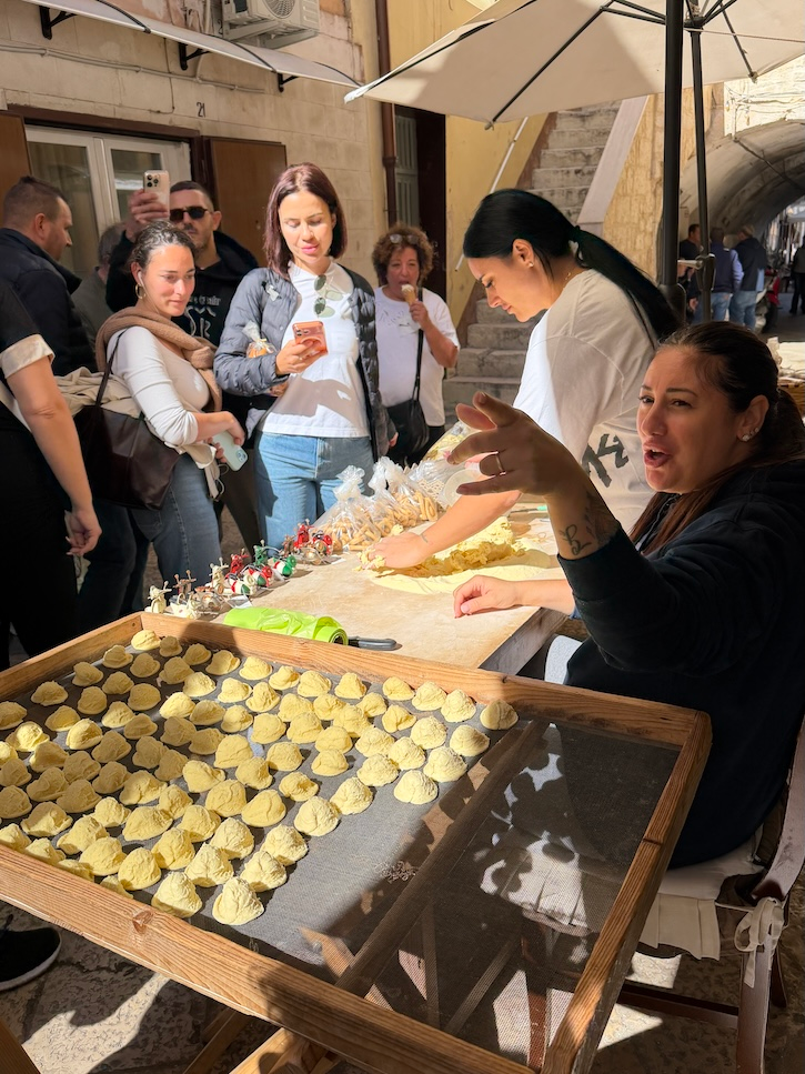 Italian women making fresh orecchiette pasta by hand on a street in Bari.